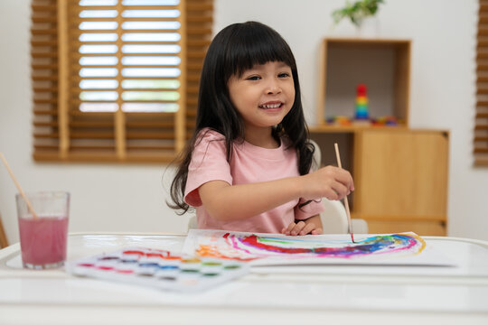 happy preschool child girl painting with watercolor on paper