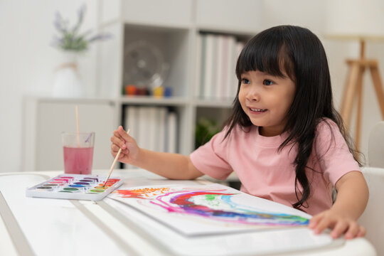 happy preschool child girl painting with watercolor on paper