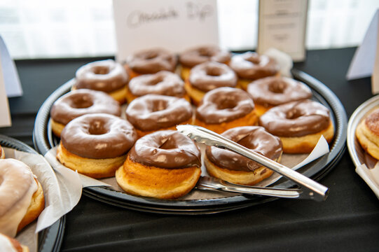 Glazed donuts on buffet table with serving tongs at catering or breakfast event
