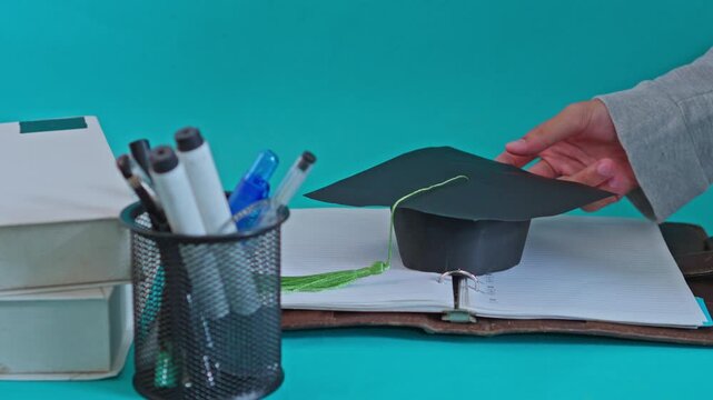Education concept featuring graduation cap being placed on study journal