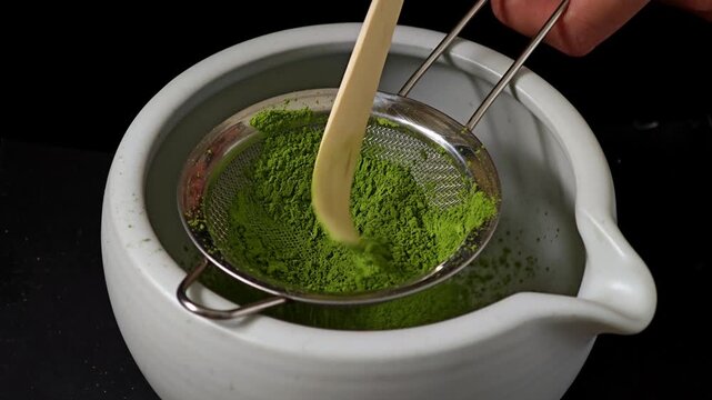 Sifting vibrant green matcha powder through a fine mesh strainer.