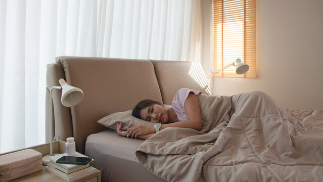 Young adult woman black asia people take herbal CBD pill bottle lying down on soft cozy bed deep sleep aid calm. Waking up happy serene relax drug anti aging good health care fall asleep well morning.
