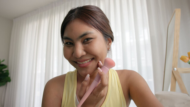 Young adult woman gen z black asia people relax get ready prepare clean makeup apply cream skin care make up getting dressed at home. Look at mirror camera self love anti aging health happy vanity.