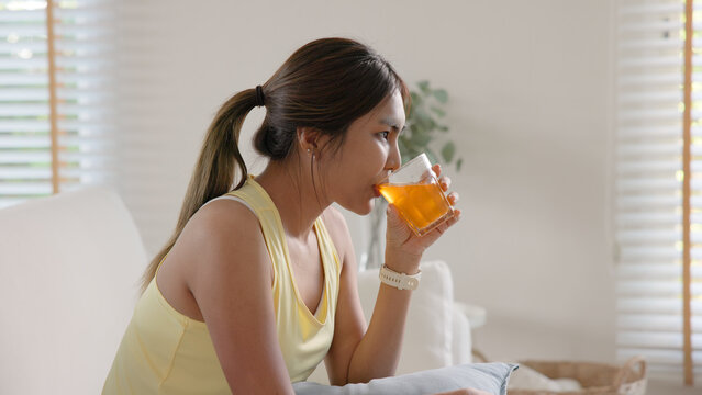 Young adult asia people happy woman drink vitamin d c e k zinc omega 3 fish oil water skin health care sit at home sofa. Take diet custom tailor made anti aging pill bottle immune weight loss herbal.