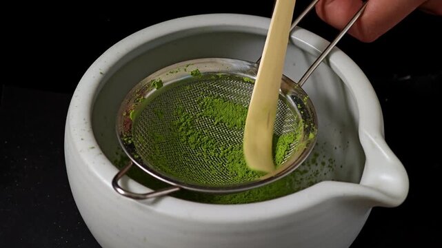 Sifting vibrant green matcha powder through a fine mesh strainer.