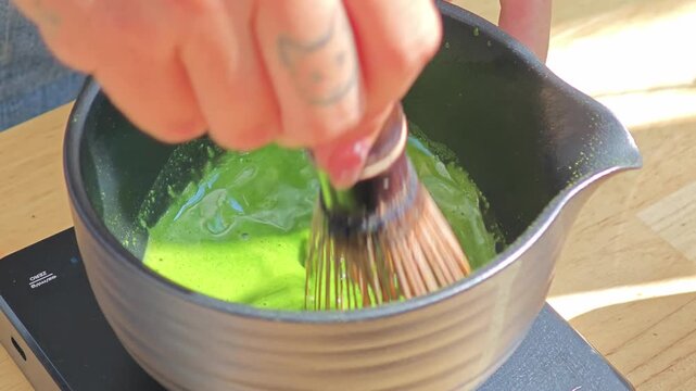 Japanese matcha powder in a bowl with bamboo whisk.