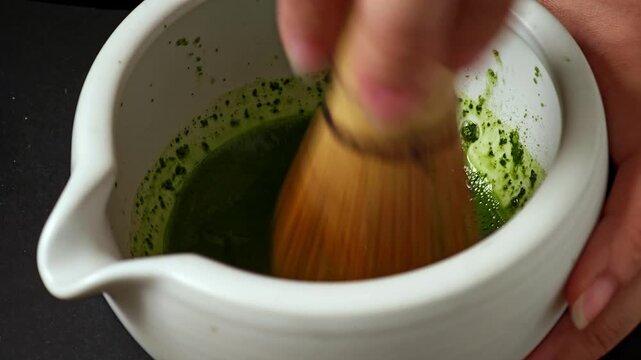 Japanese matcha powder in a bowl with bamboo whisk.