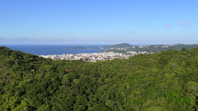 Drone sweep over Bombas and Bombinhas beaches with clear water, hills, and seaside town.