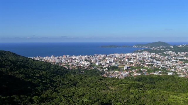 Drone reveal of Bombas and Bombinhas shoreline with waves, town buildings, and anchoring boats.