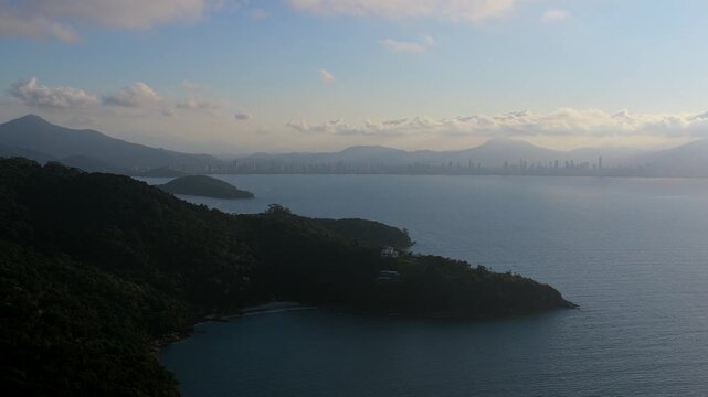 A smooth drone lift revealing the misty skyline of Itapema and Meia Praia in Brazil.