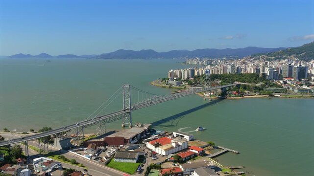 Aerial view of iconic bridge connecting Florianopolis island with mainland, showcasing urban infrastructure, coastal cityscape and transport network in Brazil.