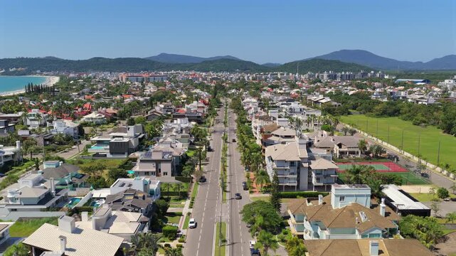 Aerial forward shot over Av. dos Buzios in Jurere Internacional, Florianopolis, showing luxury mansions and street layout.