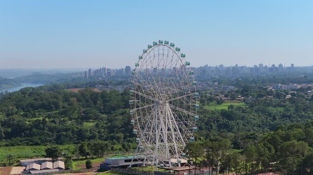 Aerial view of Yup Star Ferris wheel in Foz do Igua&ccedil;u, Brazil, with surrounding forest and skyline.