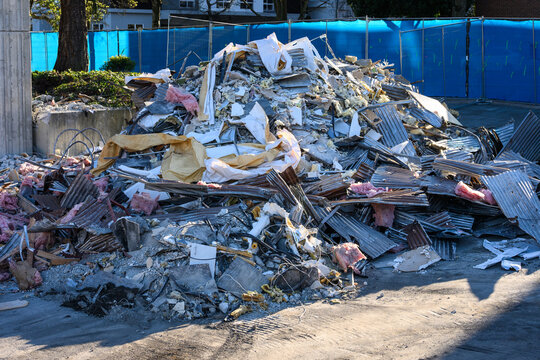 Pile of demolition debris, concrete, insulation, iron, corrugated sheet metal, old office building being demolished for urban redevelopment, sunny spring day
