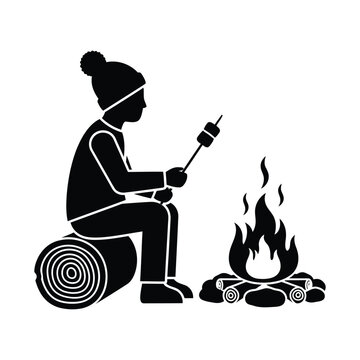 Silhouette of child sitting by campfire roasting marshmallow on stick over flames in cold weather clothes.