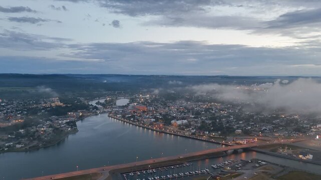 Aerial view of Matane city at dusk with river, fog, low clouds and city lights along St Lawrence River, Quebec, Canada. g.