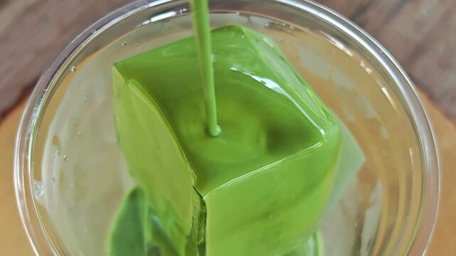 Pouring matcha latte on cube ice.
