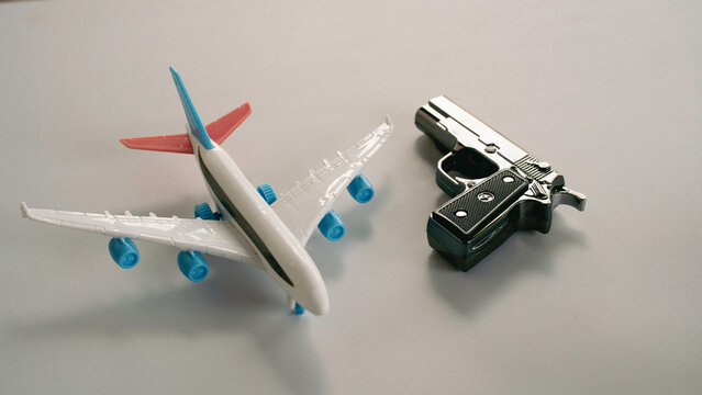 Toy Airplane and Handgun on Grey Surface Representing International Air Travel Security and Terrorism Threat
