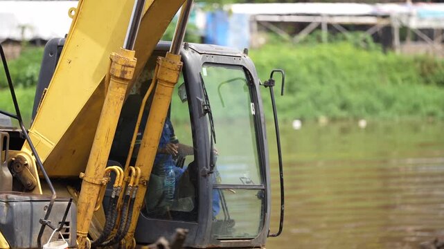 Excavator dredging polluted canal to prevent flooding and improve drainage in urban area