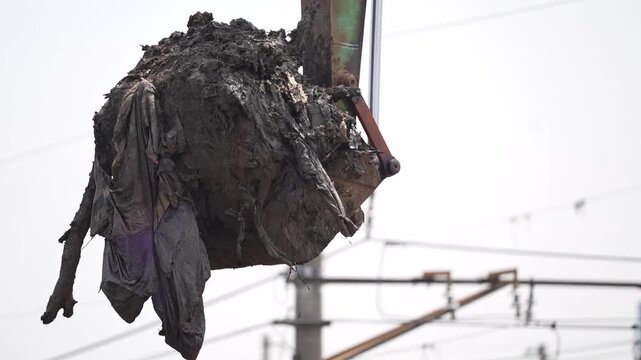 Excavator dredging polluted canal to prevent flooding and improve drainage in urban area