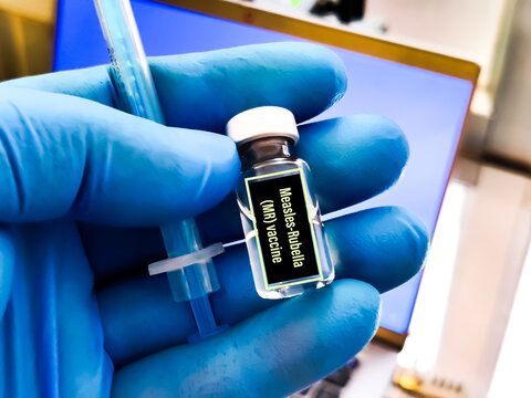 Medical syringe needle with measles, mumps, rubella label MR Or MMR vial of vaccine.