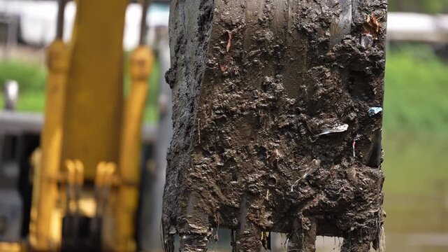 Excavator dredging polluted canal to prevent flooding and improve drainage in urban area