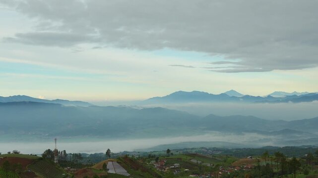 Breathtaking aerial view of misty mountains and terraced agricultural fields in the Indonesian highlands at sunrise