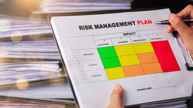 Focused worker holding risk assessment matrix on clipboard to review project management plan document with serious attention to detail
