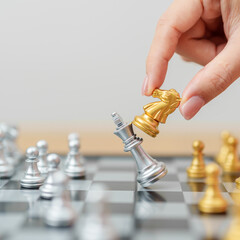 hand moving gold Chess knight figure and Checkmate opponent during chessboard competition. Strategy, Success, management, business planning, win, disruption, Trade war and leadership concept © Jo Panuwat D