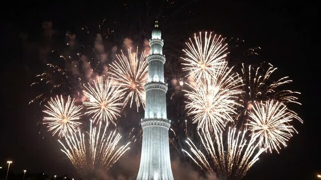 Fireworks exploding above a tall minaret tower at night mosque event sky explosion