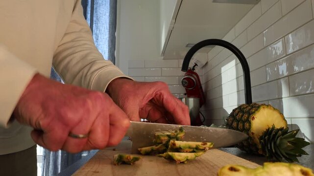 Stockholm, Sweden A cook slice a pineapple on a cutting board. 