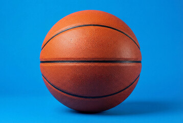 Fototapeta premium Professional orange basketball isolated on solid blue background with studio lighting and texture details