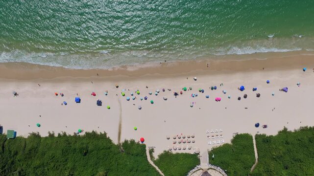 Jurer&ecirc; Internacional in Florian&oacute;polis Santa Catarina Brazil on Atlantic Ocean with top down view of beach umbrellas, shoreline waves, and formal access path with vegetation edges, drone top down later