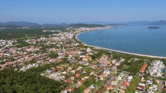 Aerial view of Praia Cachoeira do Bom Jesus in Florianopolis, Brazil with curved beach, coastline and residential area.