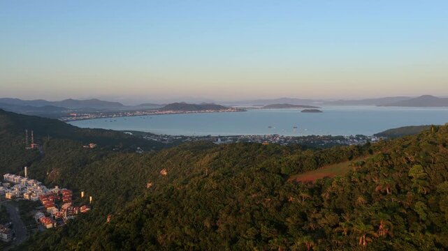 Aerial drone view of green hills and the neighborhoods of Cachoeira do Bom Jesus and Canavieiras in Florianopolis Brazil.