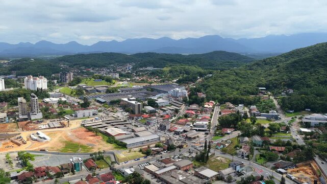 Aerial drone view of Joinville city with urban neighborhoods lush green vegetation and mountains in Brazil.