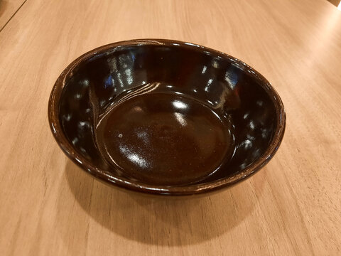 A black ceramic bowl sitting on a wooden table