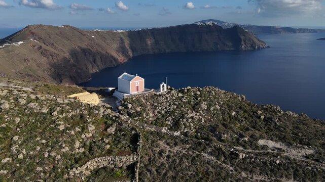 Dramatic aerial view of the volcanic cliffs and caldera of Santorini island, Greece. A wide drone shot highlighting the natural geological formations and the vast Mediterranean ocean