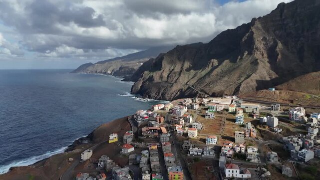 Cinematic aerial panorama of Ponta do Sol coastline in Santo Antao, Cape Verde. Drone footage of the urban settlement nestled between massive volcanic cliffs and the Atlantic Ocean travel holiday