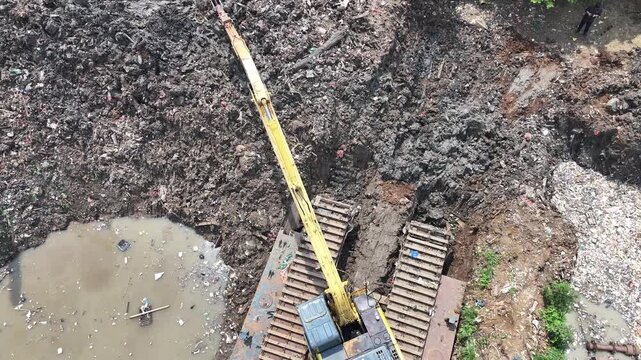 Aerial view The blue and yellow excavator is working to dig and clean the river from mud and rubbish, removing it to the edge of the river middle city