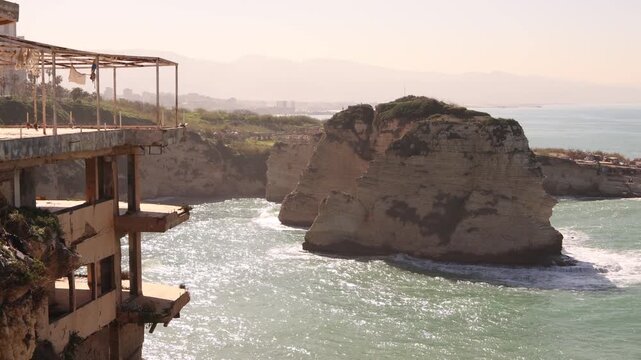 A scenic view of a derelict, abandoned concrete building perched on the limestone cliffs of Raouche in Beirut. The ruins overlook the Mediterranean Sea