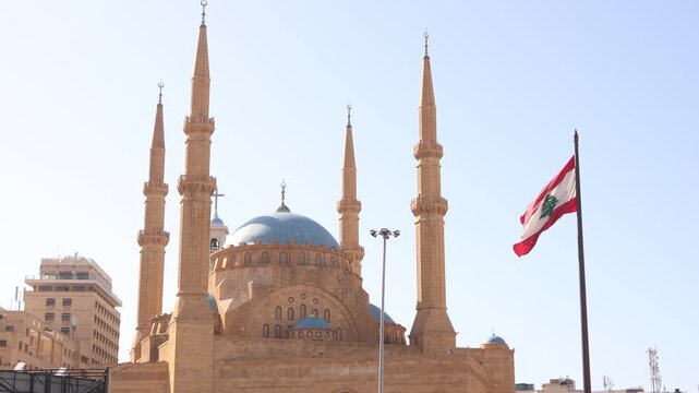 Mohammad Al-Amin Mosque with the Lebanese flag waving in the foreground. Iconic spiritual and national symbols in the heart of downtown Beirut, Lebanon