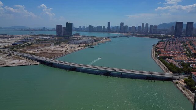Kuala Juru river bridge connecting land reclamation and residential area with Georgetown city skyline and hills in background. Great aerial view static panorama hovering drone