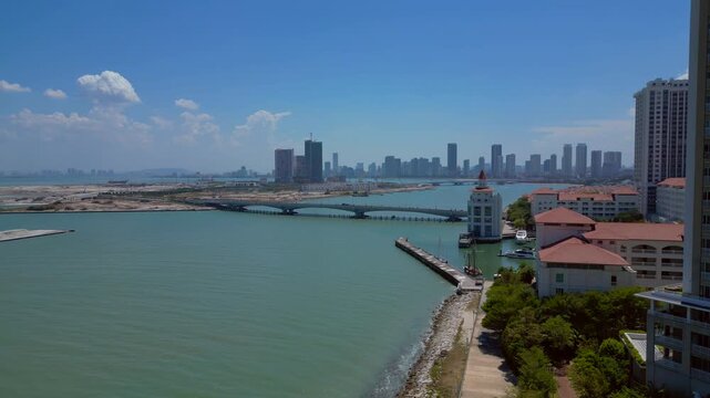 Kuala Juru river bridge connecting land reclamation and residential area with Georgetown city skyline and hills in background. Magic aerial view drone shot panorama from above