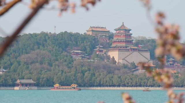 Beautiful panoramic view of ancient Chinese architecture at Summer Palace with traditional boat on the water and historic pavilion on the hill during spring season in Beijing