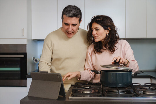 Couple Using Tablet for Cooking. Couple using tablet for digital recipe while cooking at home kitchen