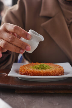 Enjoying kunefe at a cafe with pastry and sauce