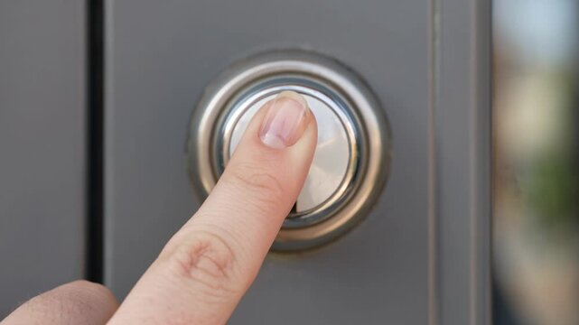 Close Up of a Finger Pressing a Silver Doorbell on a Modern Door