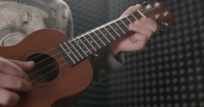 Boy Play Music on Ukulele Instrument in Home Studio. 4K 10-bit