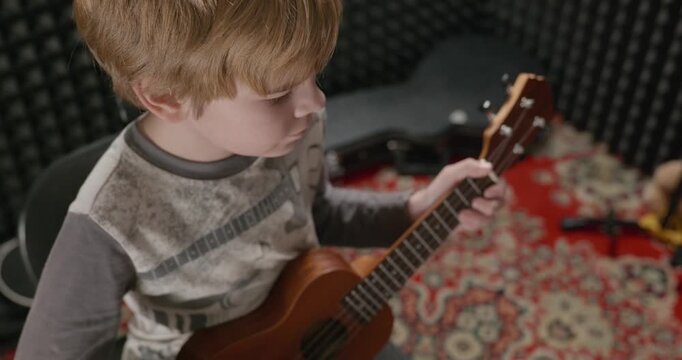 Boy Play Music on Ukulele Instrument in Home Studio. 4K 10-bit